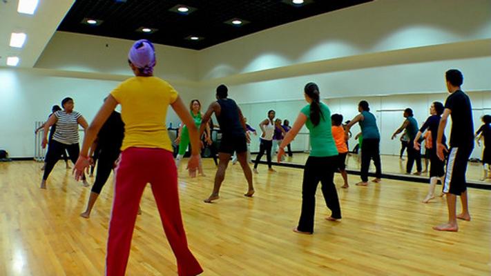 Group of dancers stepping side to side with arms pushing forward